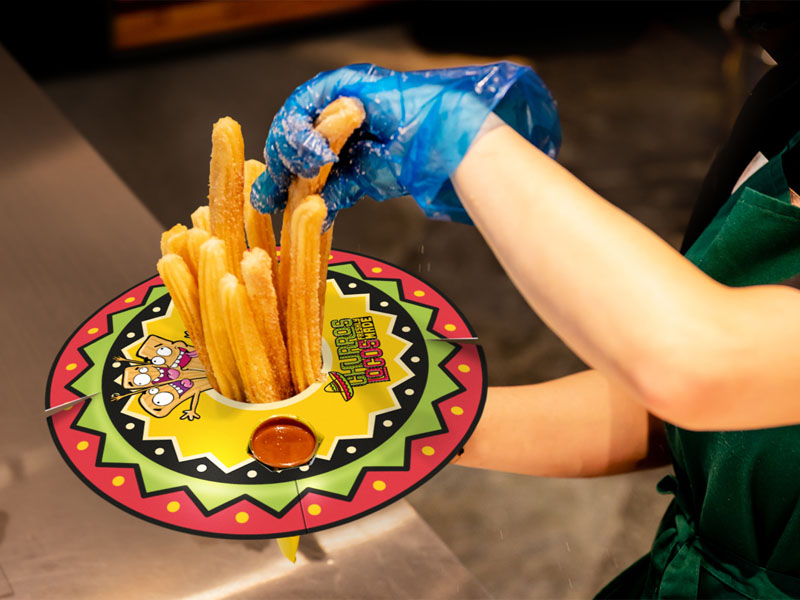 A brightly coloured sombrero style serving hat holding fresh churros